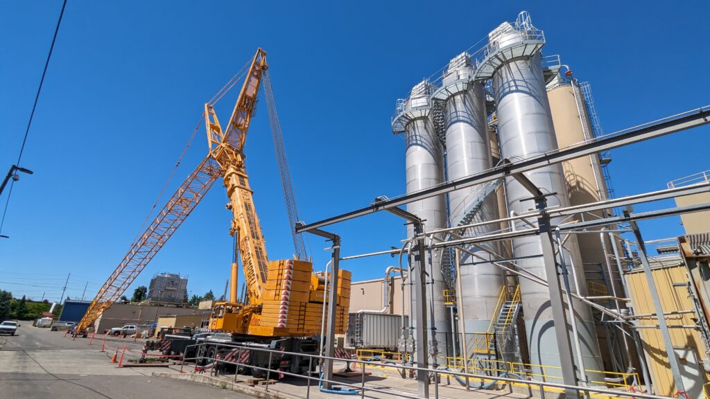 Large construction crane positioned beside newly installed stainless-steel flour silos at a food manufacturing facility in Portland, Oregon, during an industrial engineering upgrade managed by T&M Design