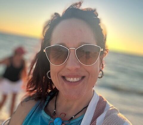 Cory McNabb standing on a beach smiling with sunglasses on.