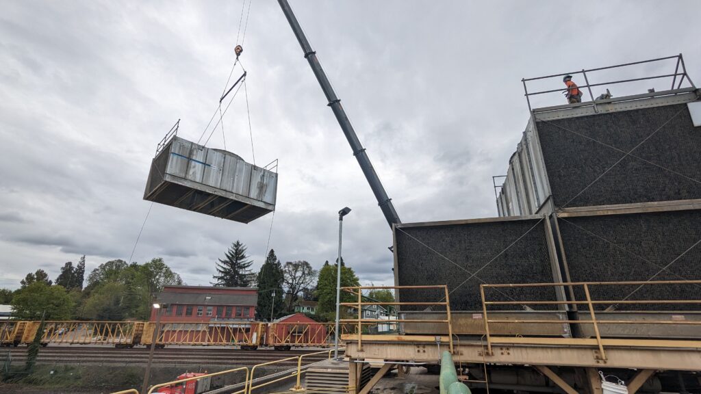 Crane lifting a component for water towers on a cloudy day.