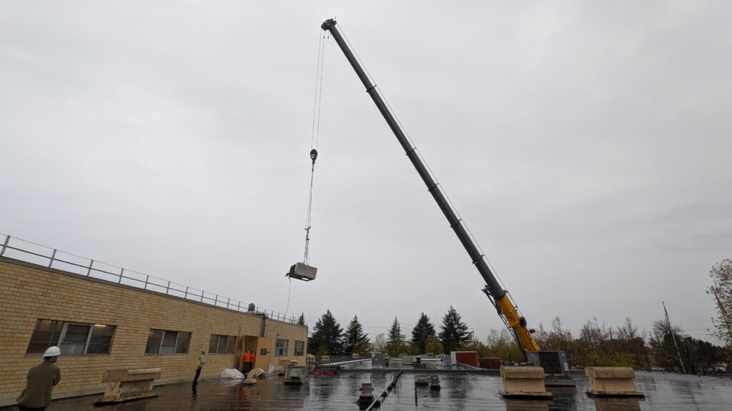Large crane lifting commercial oven unit away from a food processing facility
