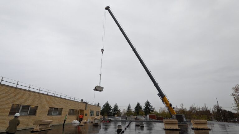 Large crane lifting commercial oven unit away from a food processing facility