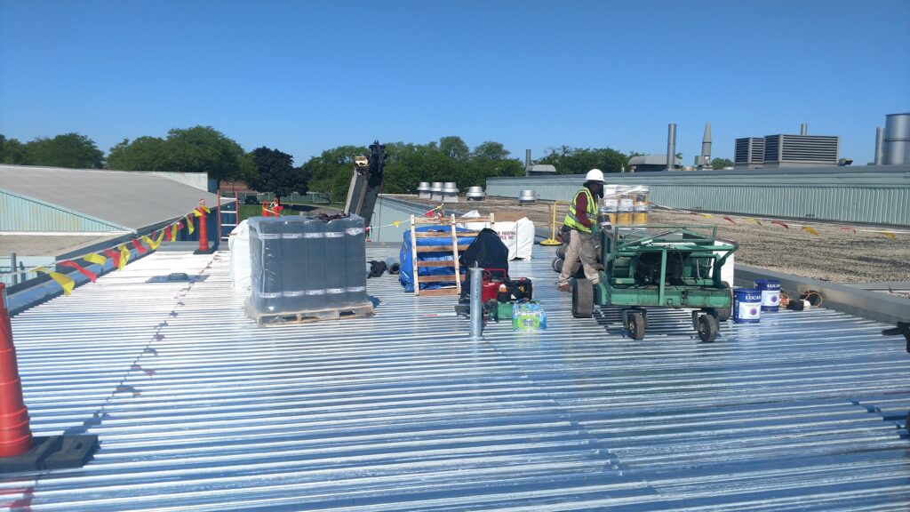 Metal roof at an industrial engineering facility under construction with workers and materials on it