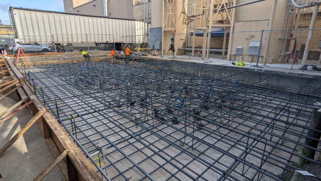 Workers on an manufacturing facility construction site laying rebar as a foundation.
